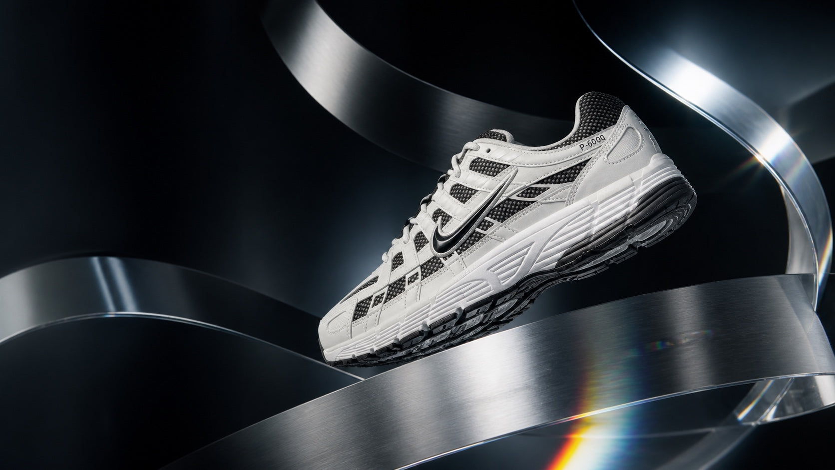 Nike P-6000 Sail Phantom Off-Noir suspended between brushed steel ribbons